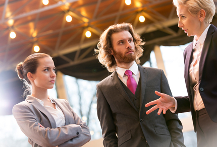 A man and two woman in business attire having a serious conversation.