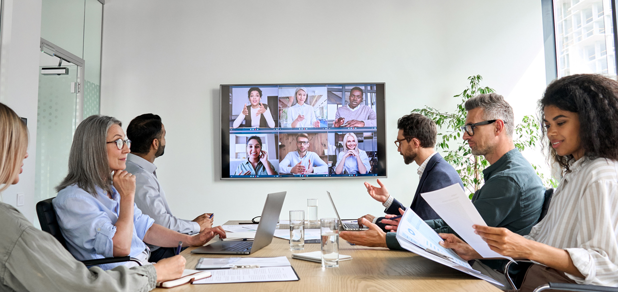Employees gathered in a meeting room having an online conference video call.